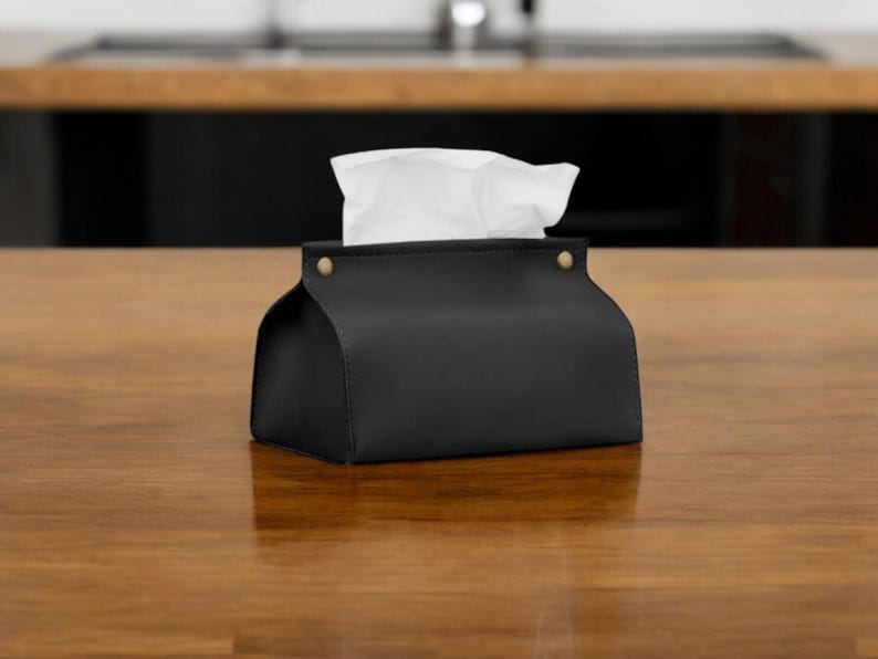 Boîte à mouchoirs design haut de gamme avec finition en cuir pour salon ou bureau Une boîte à mouchoirs chic avec une finition en cuir de luxe, idéale pour une décoration élégante.