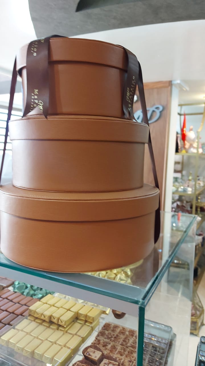 Coffret chocolat rond de luxe pour entreprise avec assortiment de chocolats artisanaux.