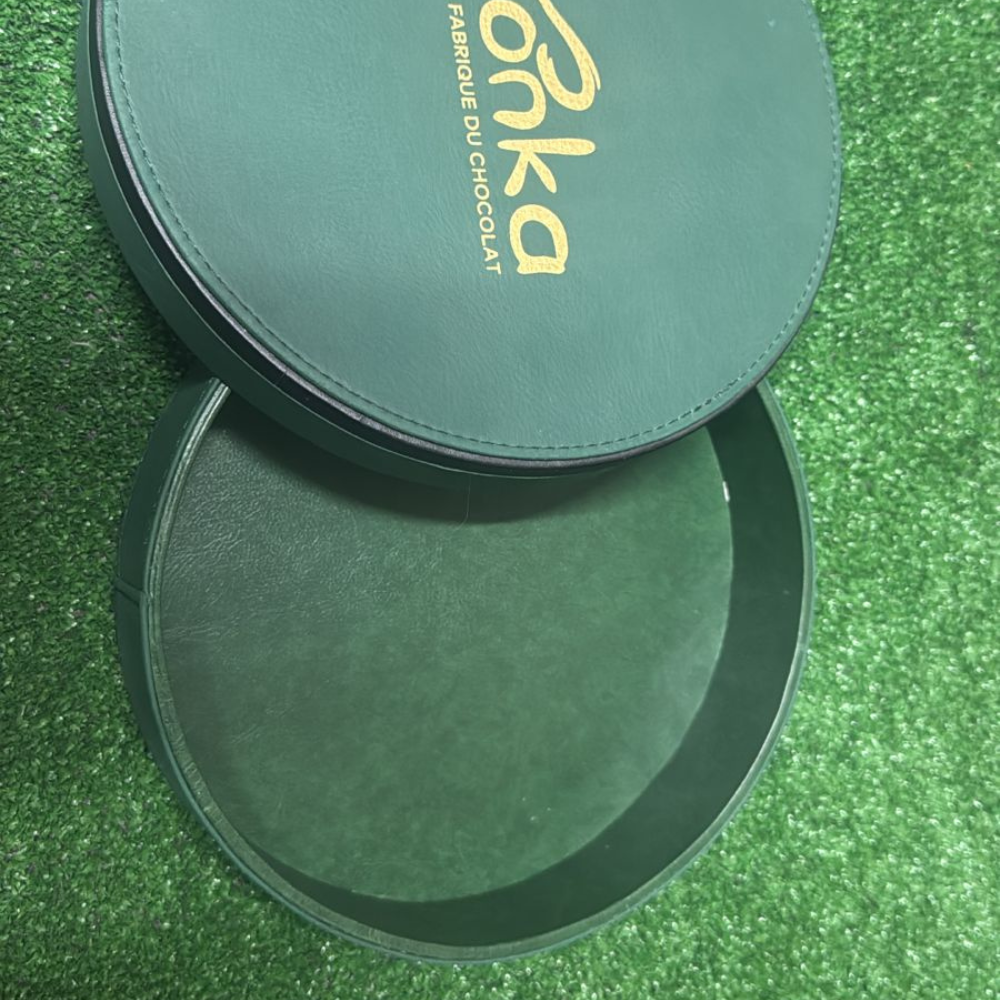 Coffret cadeau rond vert contenant des chocolats de luxe.