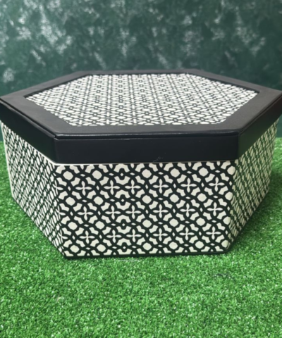 Boîte cadeau anniversaire vide de forme hexagonale avec un motif géométrique noir et blanc distinctif et un intérieur sombre.