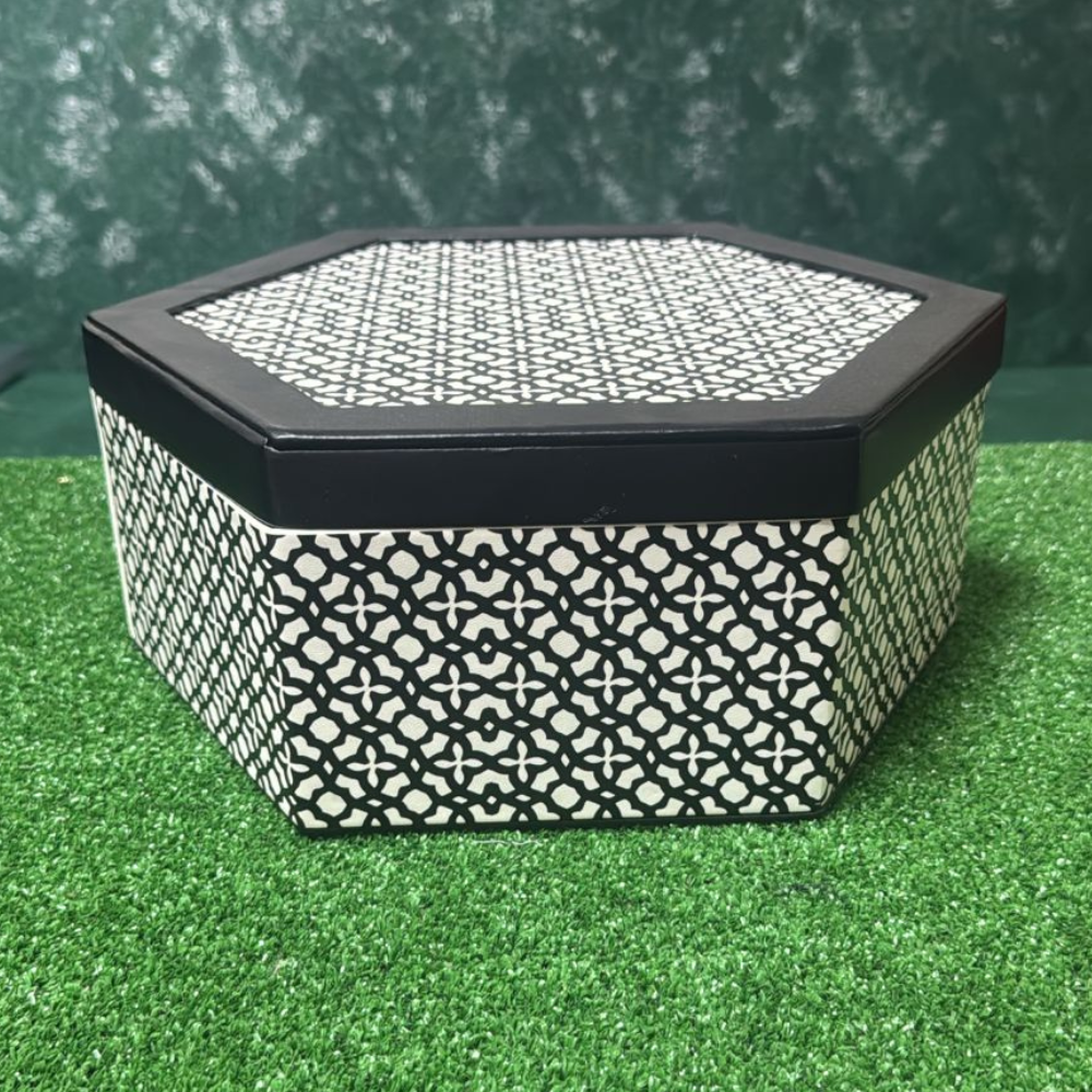 Boîte cadeau anniversaire vide de forme hexagonale avec un motif géométrique noir et blanc distinctif et un intérieur sombre.